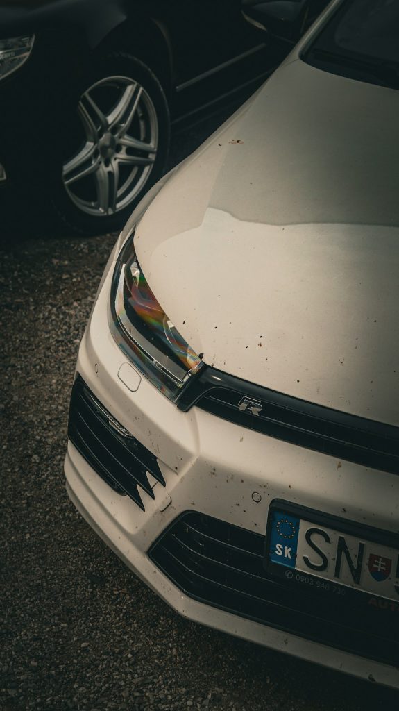 a-close-up-of-a-white-car-parked-in-a-parking-lot-kk-zjcqzl9u