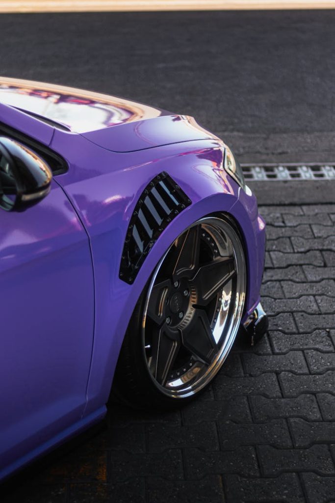 Close-up view of a purple cars front wheel showcasing sleek design and vibrant color.